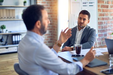 Two male employees talking at work