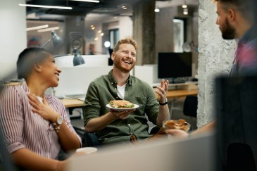Group of people sitting together and laughing, eating