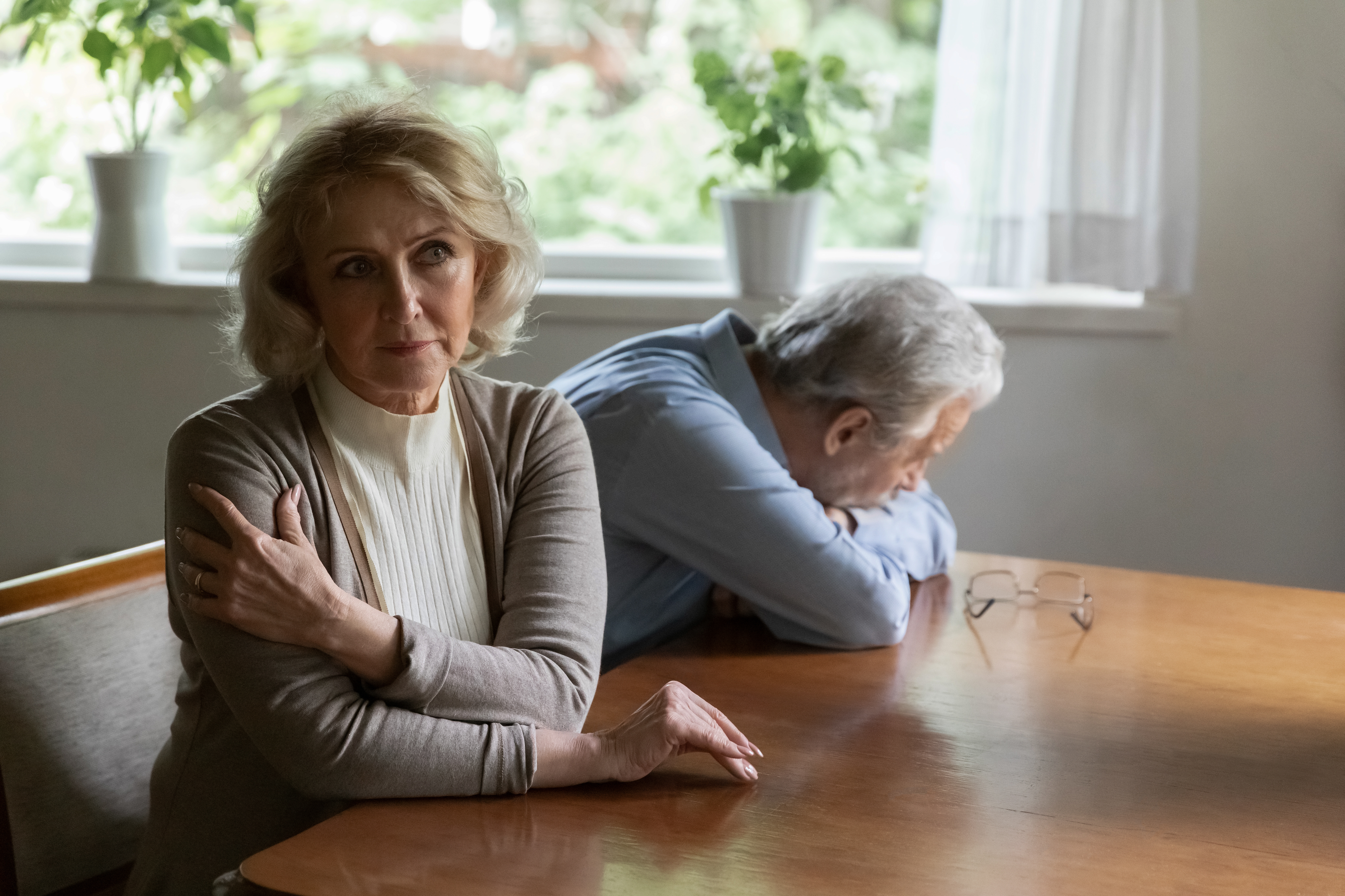 Older couple sitting with backs facing each other; upset