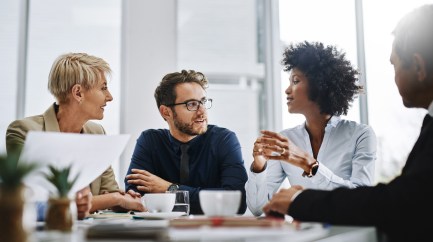 A group of colleagues sit at a conference, deep into a discussion.