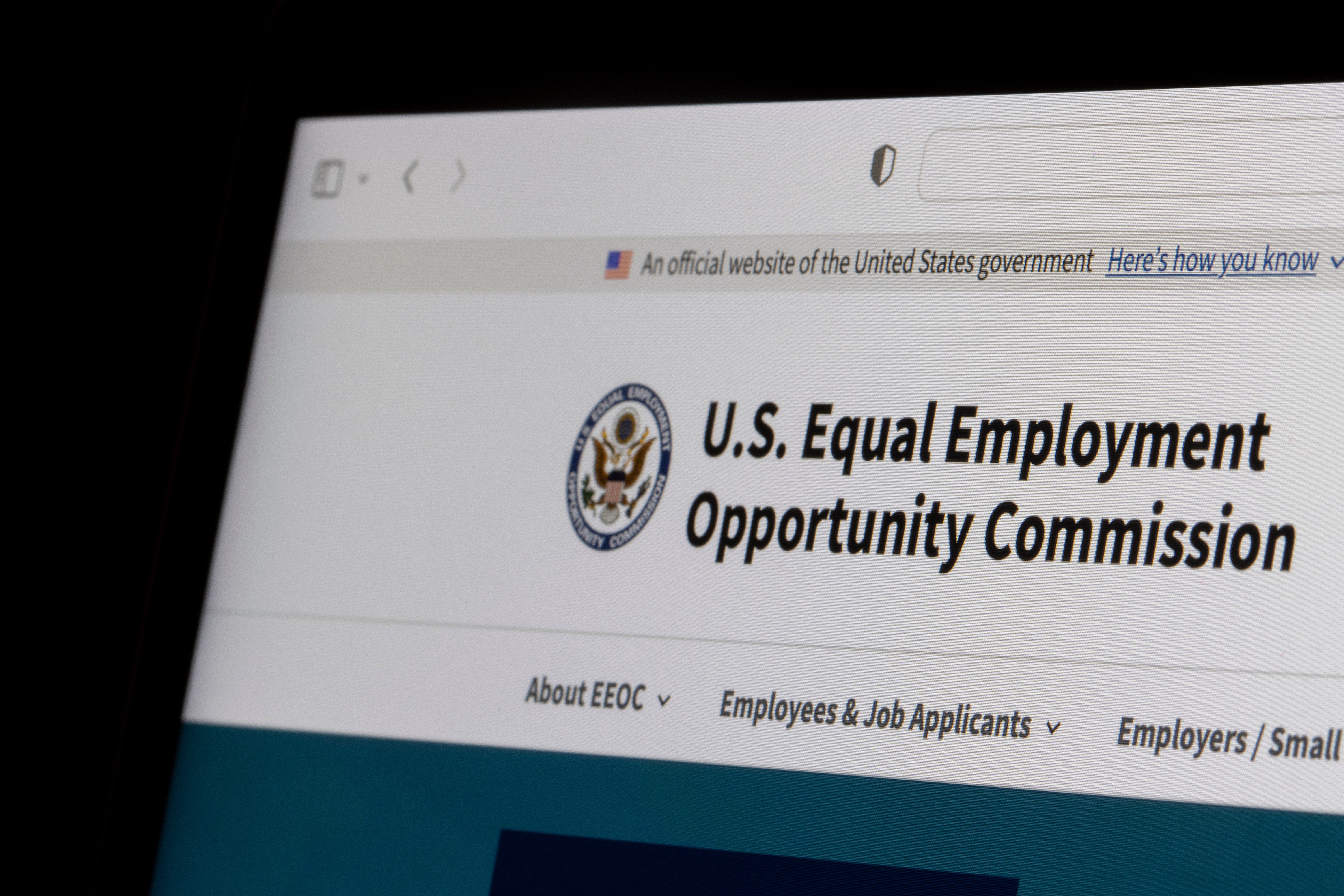 The EEOC's web page is visible only at the top of the computer screen.