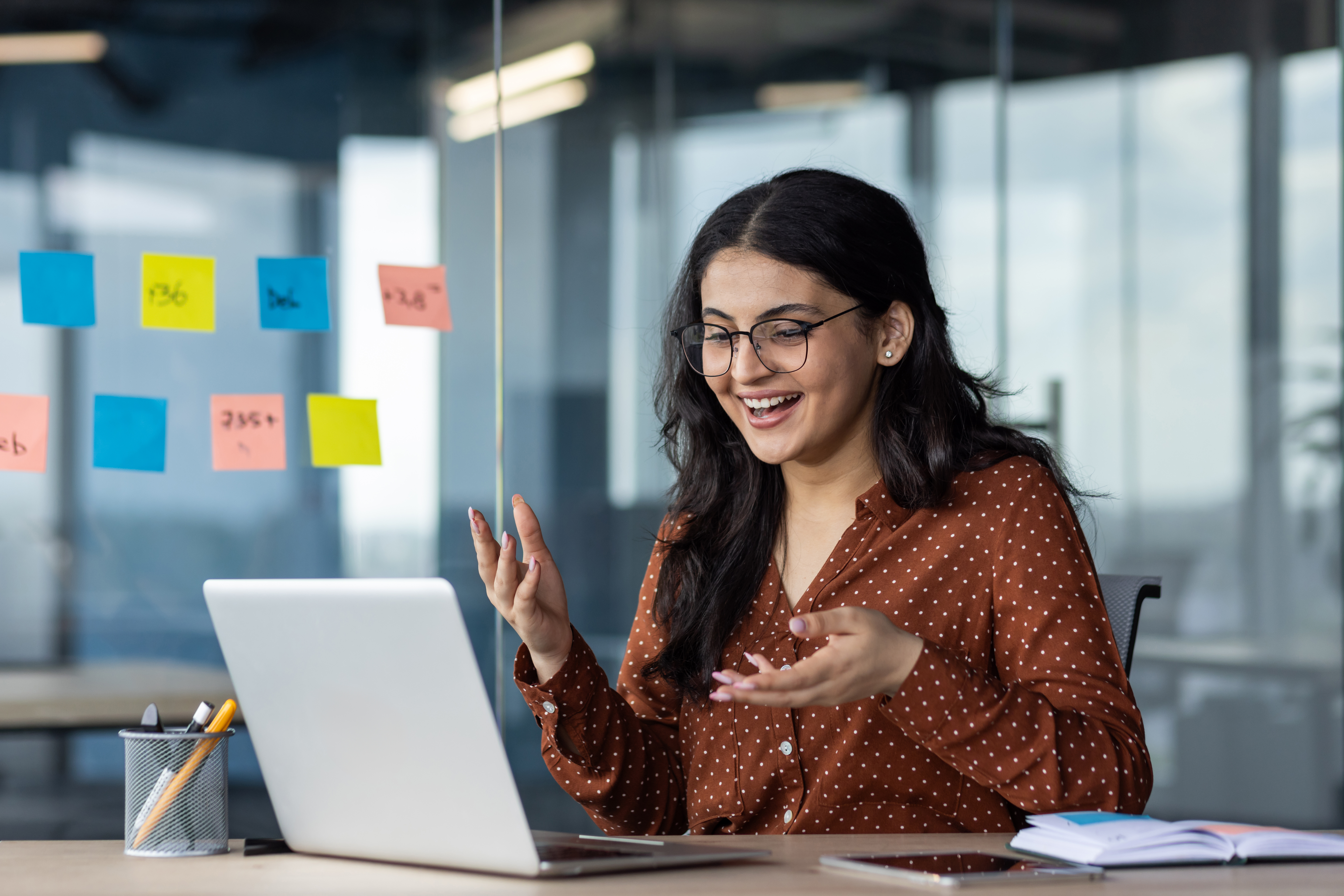 Woman working on laptop, talking with someone on screen