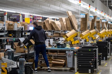Amazon warehouse worker tagging boxes.
