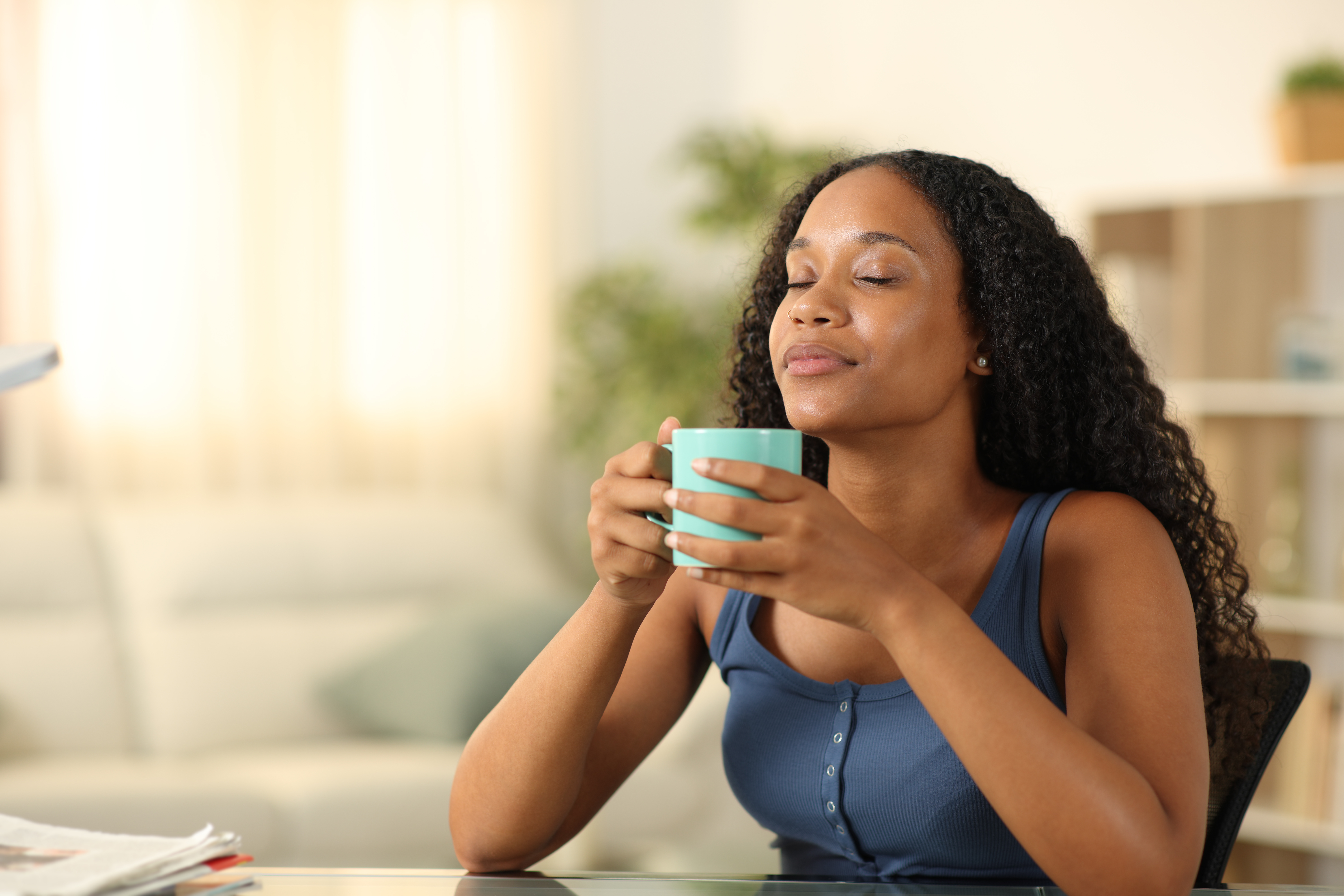 A woman with her eyes closed in peace holds a cup of coffee.