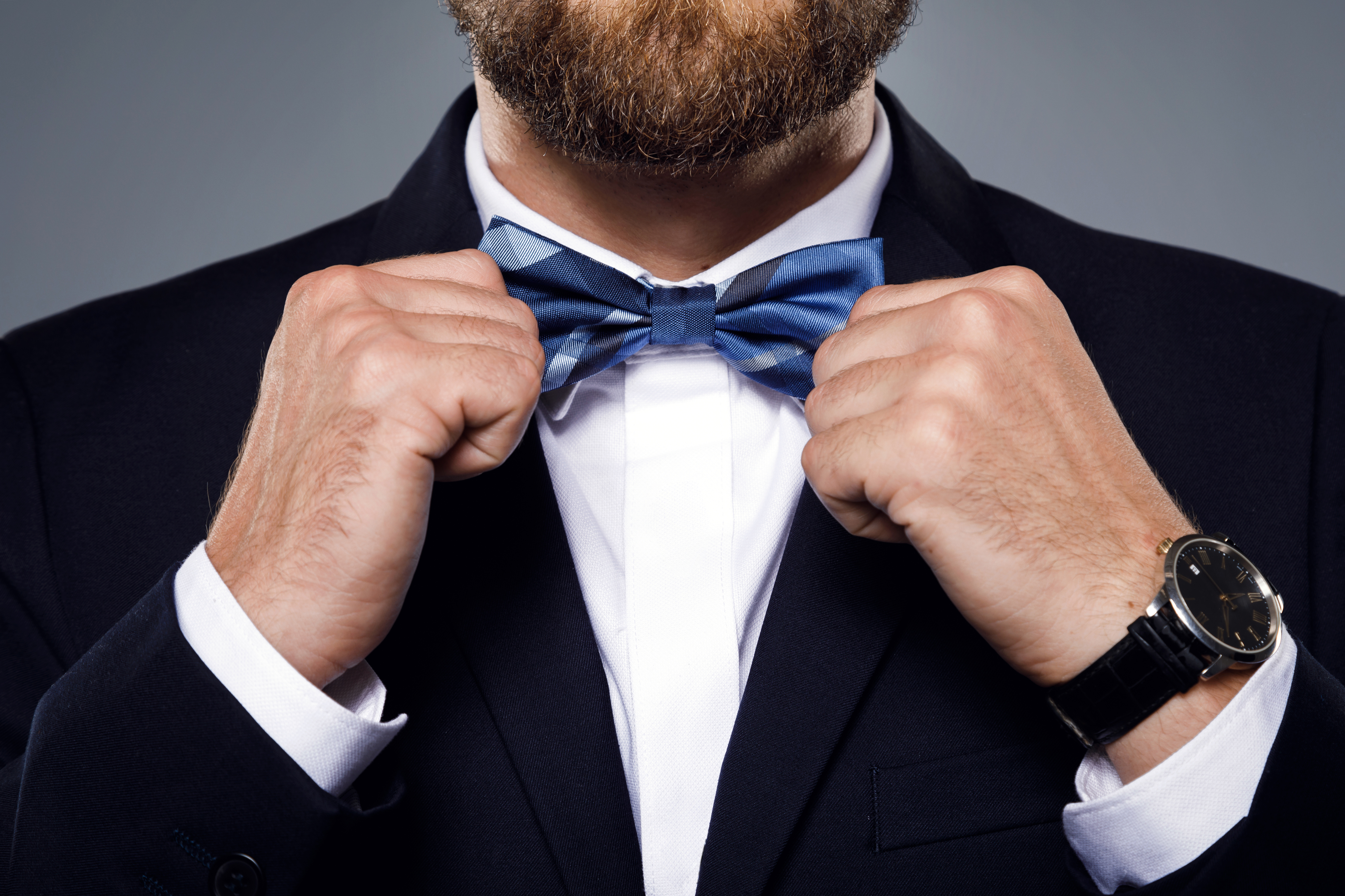 Man in suit straightening bow tie