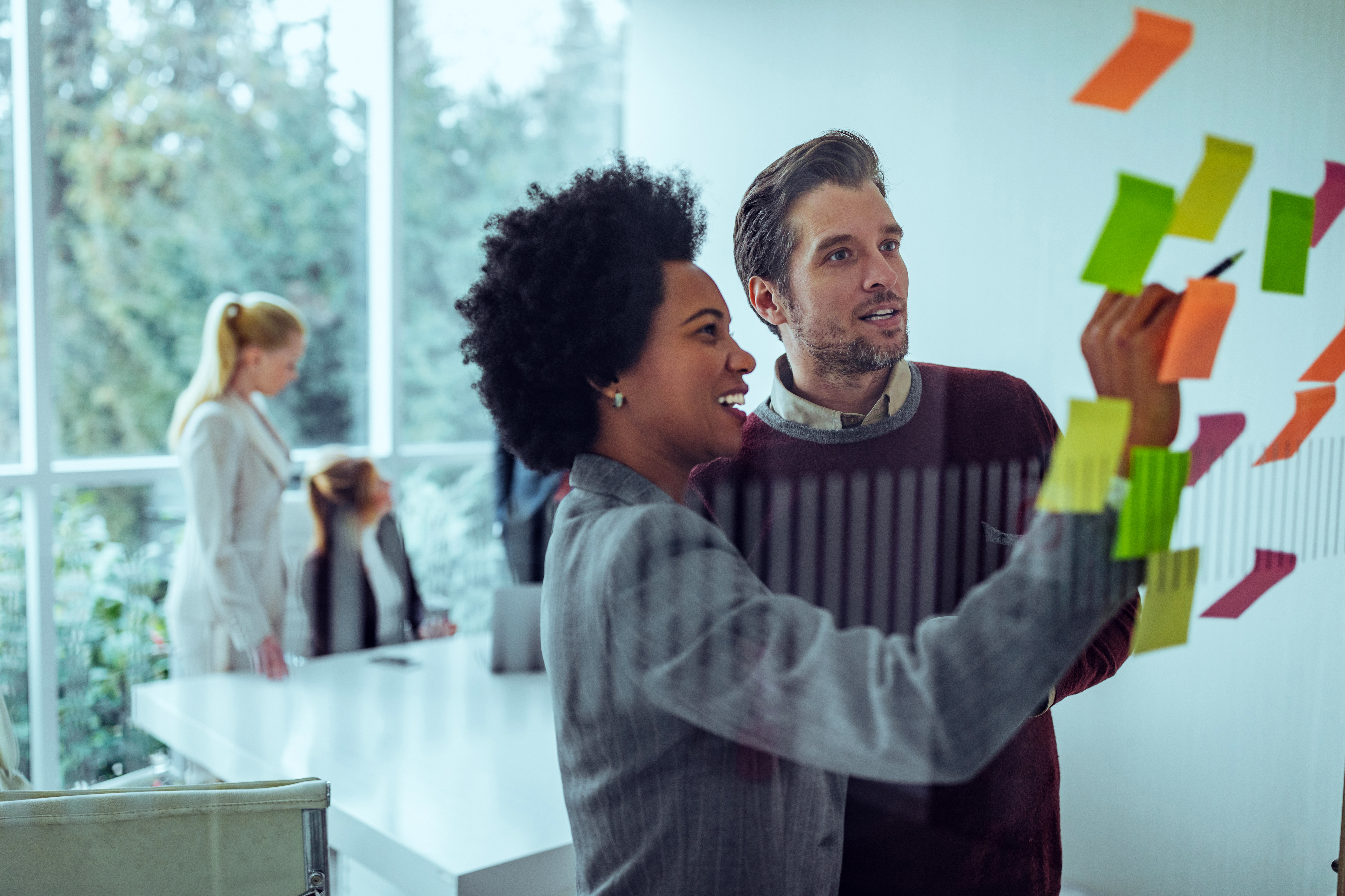 Employee working together putting sticky notes on glass
