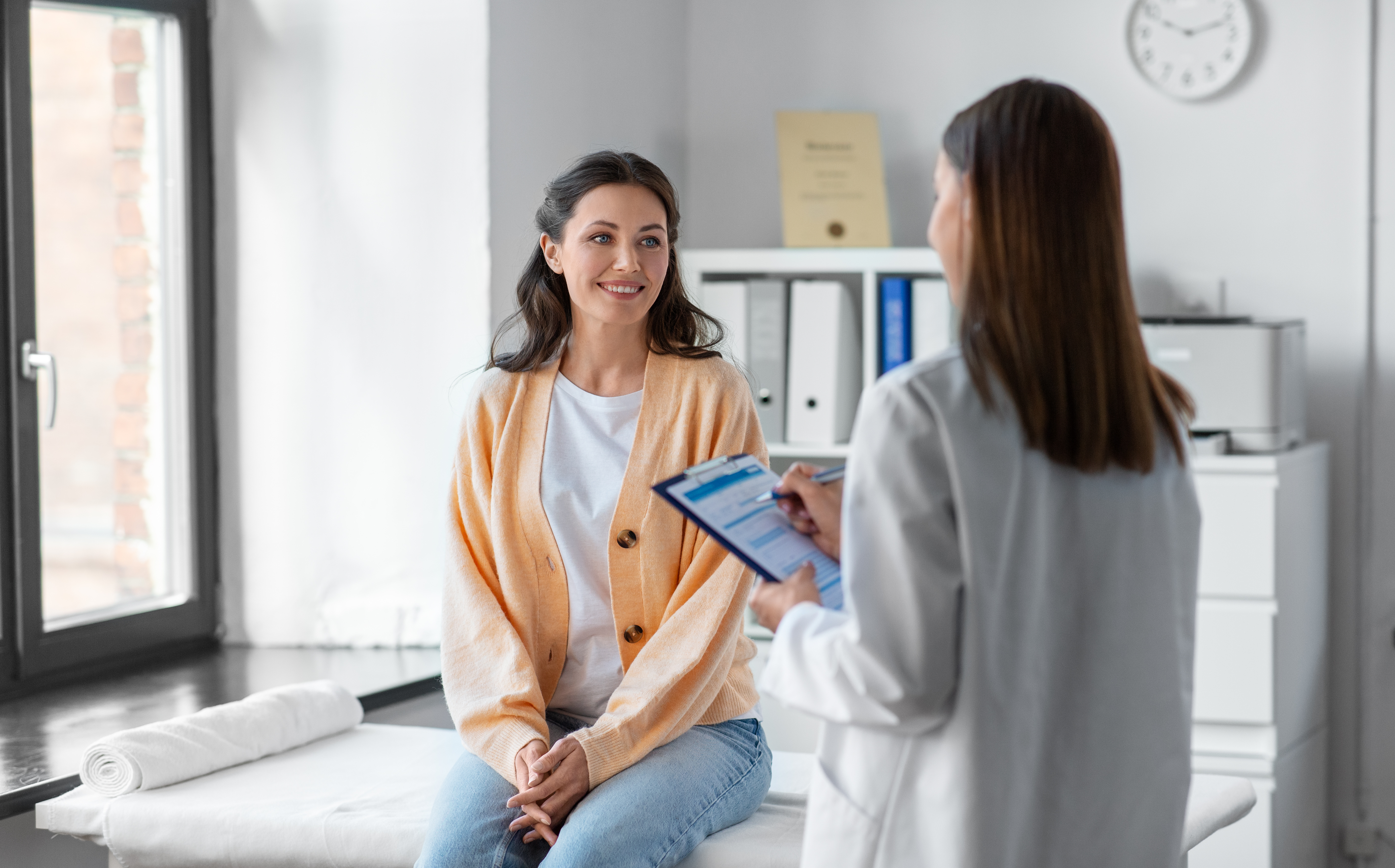 A woman sits while her doctor speaks to her.