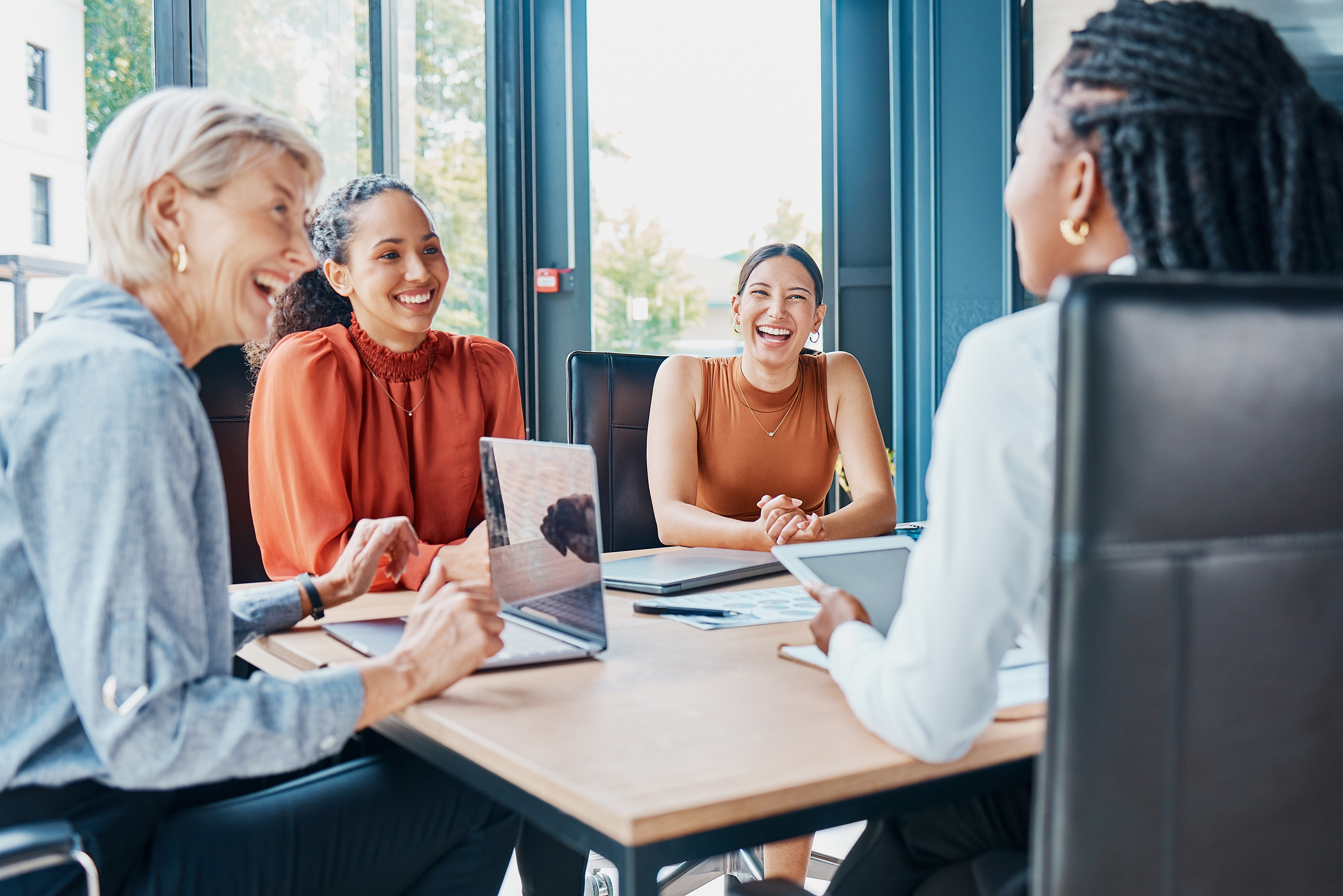 Women in office sitting around table, laughing