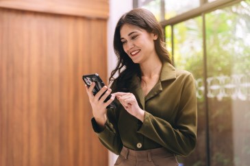 Woman looking at screen of cell phone, smiling