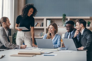 Group of employees working around table, talking and laughing