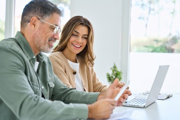 Couple looking at paper and working on laptop, smiling
