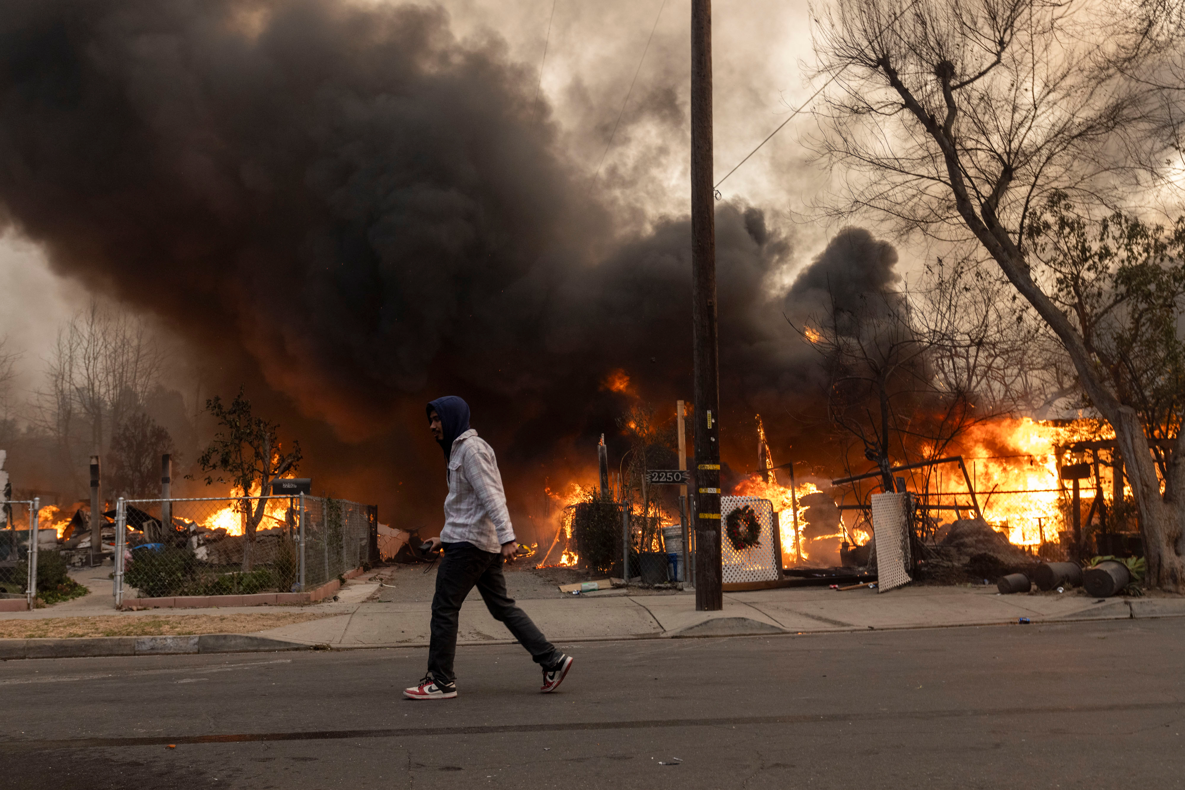 Man walking past burning homes