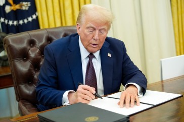 US President Donald Trump signs an executive order in the Oval Office.
