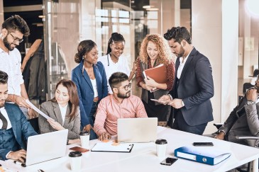Group of employees sitting and standing around a table