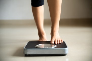 A woman is stepping on a scale to weigh herself.