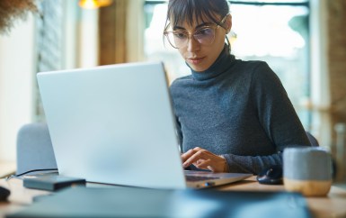 Woman working on laptop with coffee cup next to her