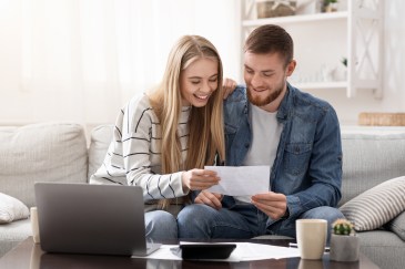 Man and woman, couple, sitting on couch looking at papers