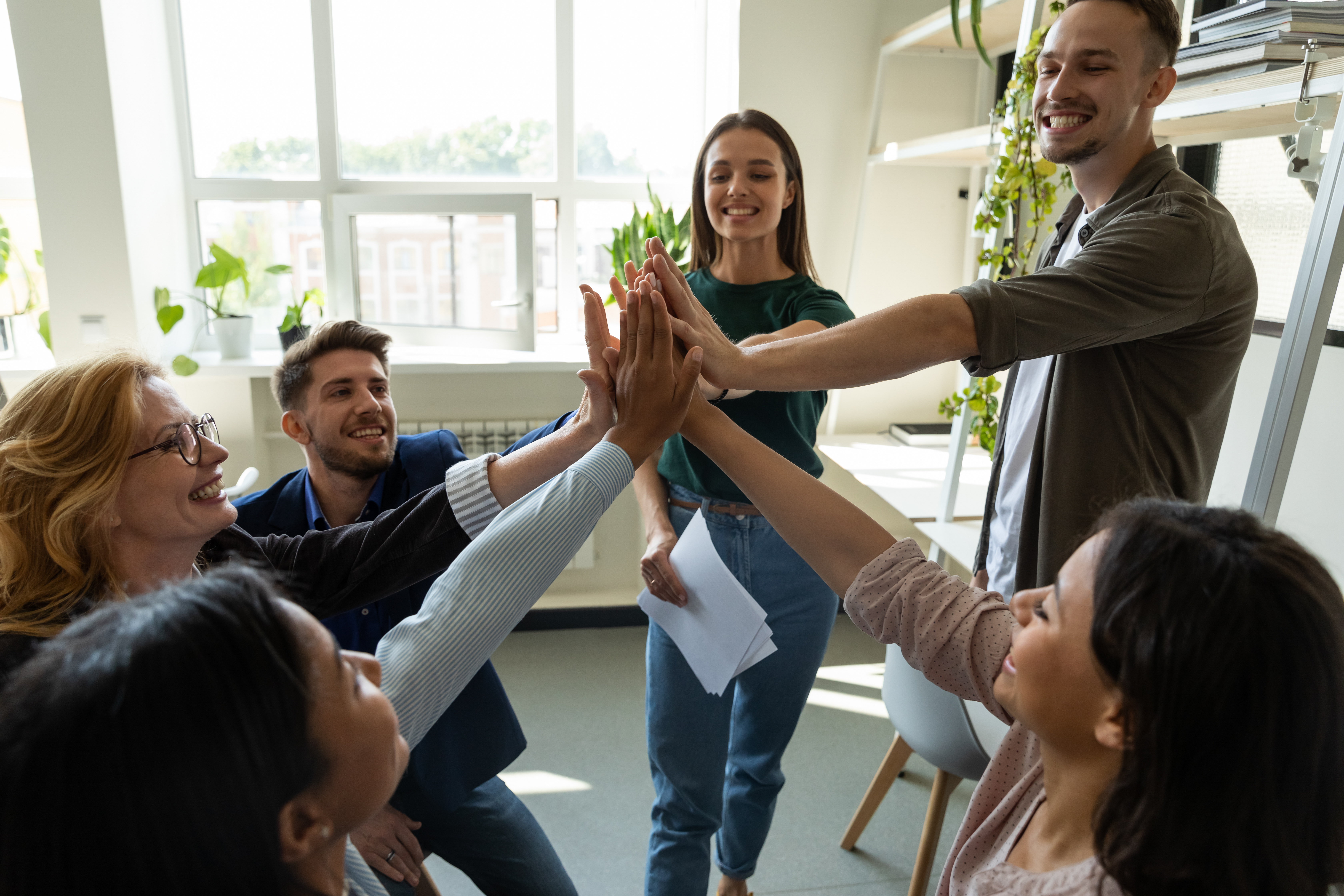 Group of employees working together, high-fiving