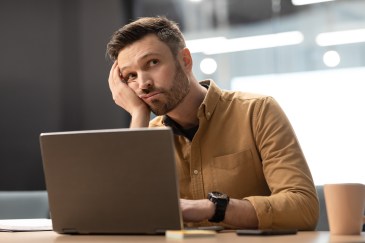 Man looking off into the distance while sitting at his computer