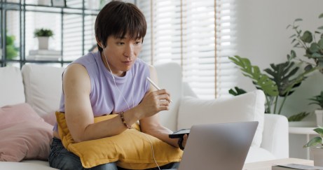 Young man sitting in front of a computer while holding a cell phone