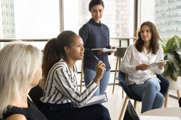 Group of young, diverse employees sitting in office talking