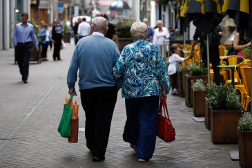 An elderly couple walk arm-in-arm past an outdoor cafe terrace in Edinburgh, U.K., on Wednesday, July 31, 2013. The latest opinion polls show supporters of Scottish First Minister Alex Salmond's campaign for independence lagging behind those in favor of the status quo by more than 20 percentage points ahead of the Sept.18, 2014, referendum. Photographer: Simon Dawson/Bloomberg