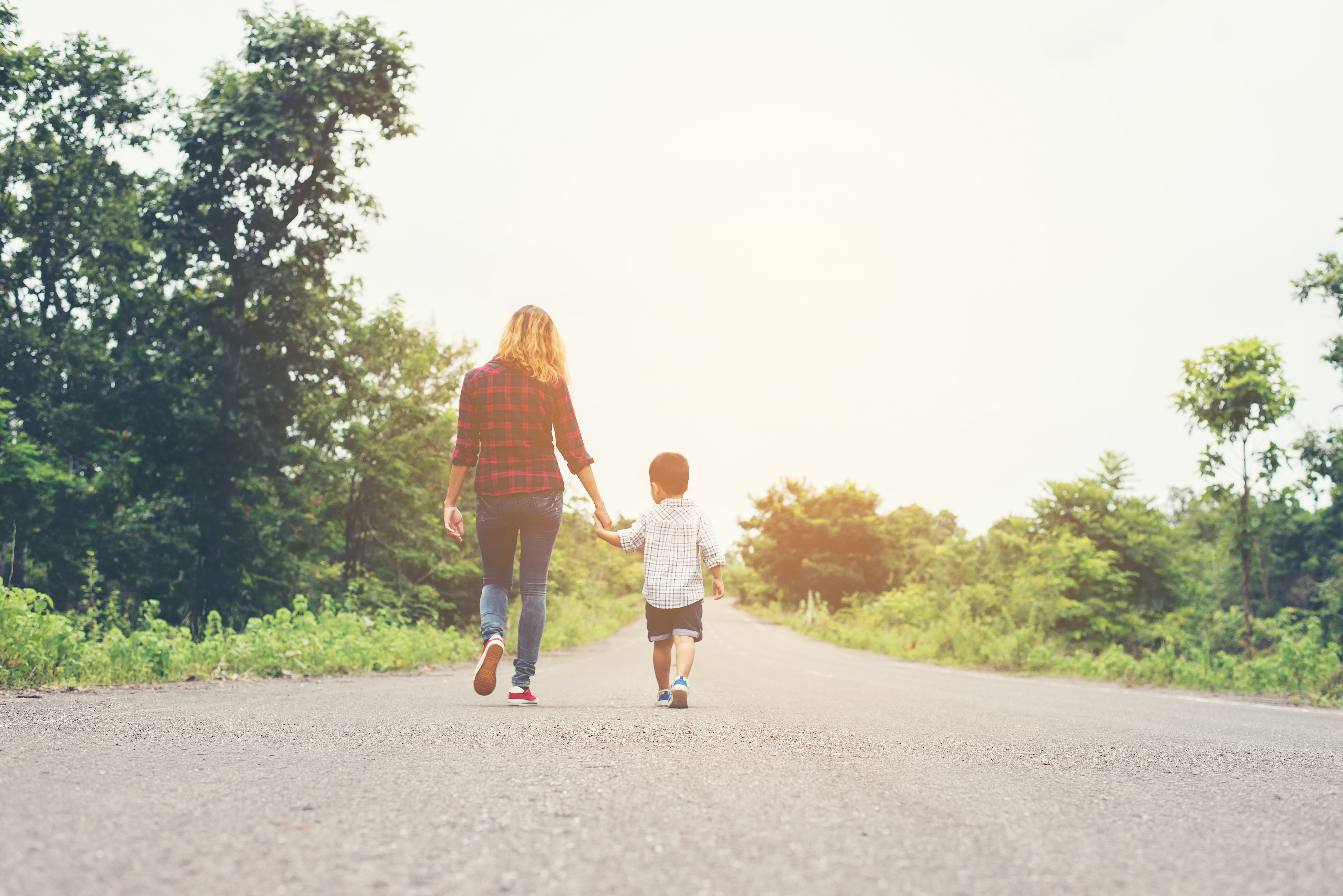 Mom holding son's hand walking on road