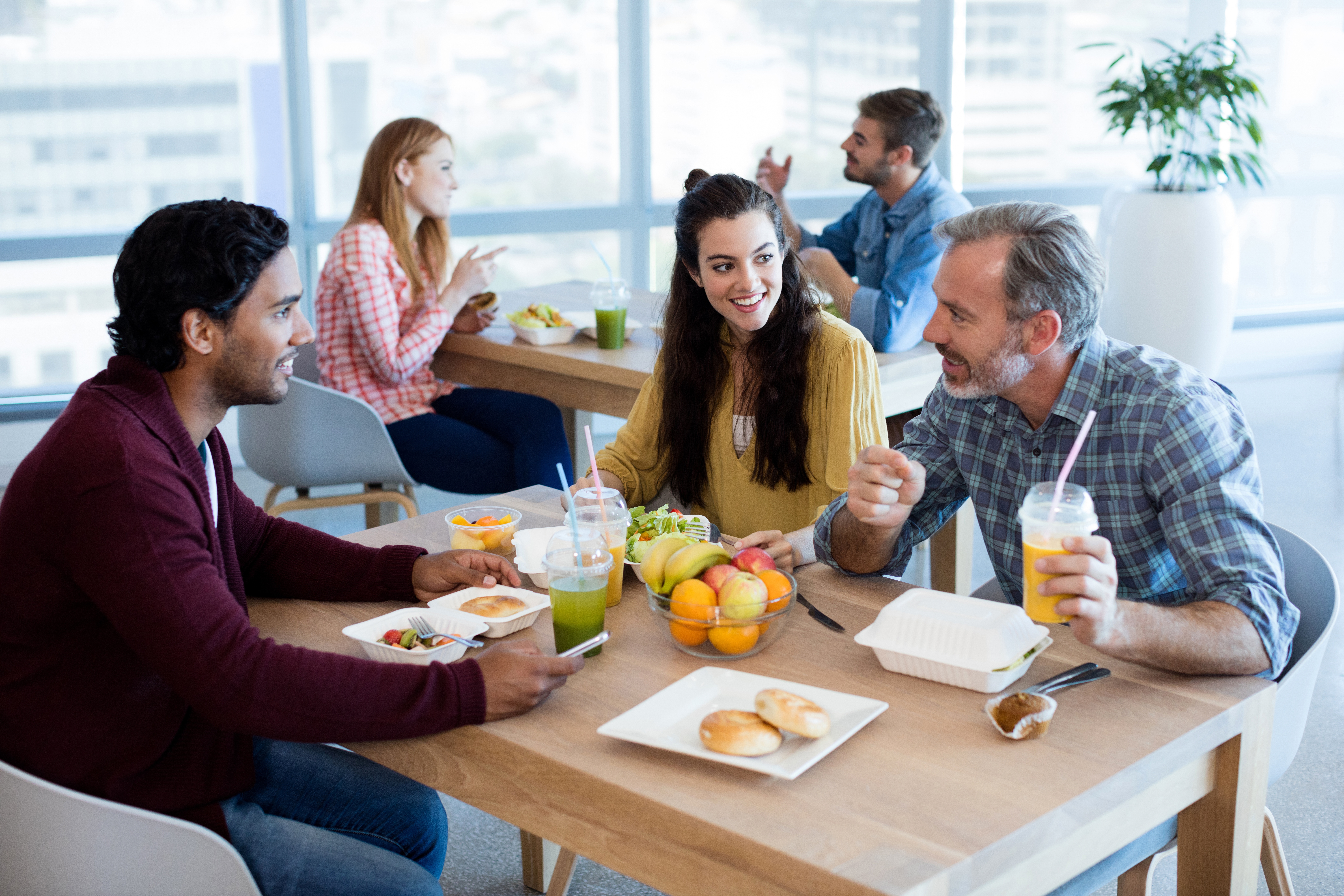 Employees sitting at table eating lunch, talking, healthy