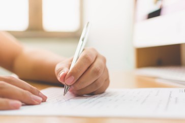Woman's hands, filling out paperwork with pen