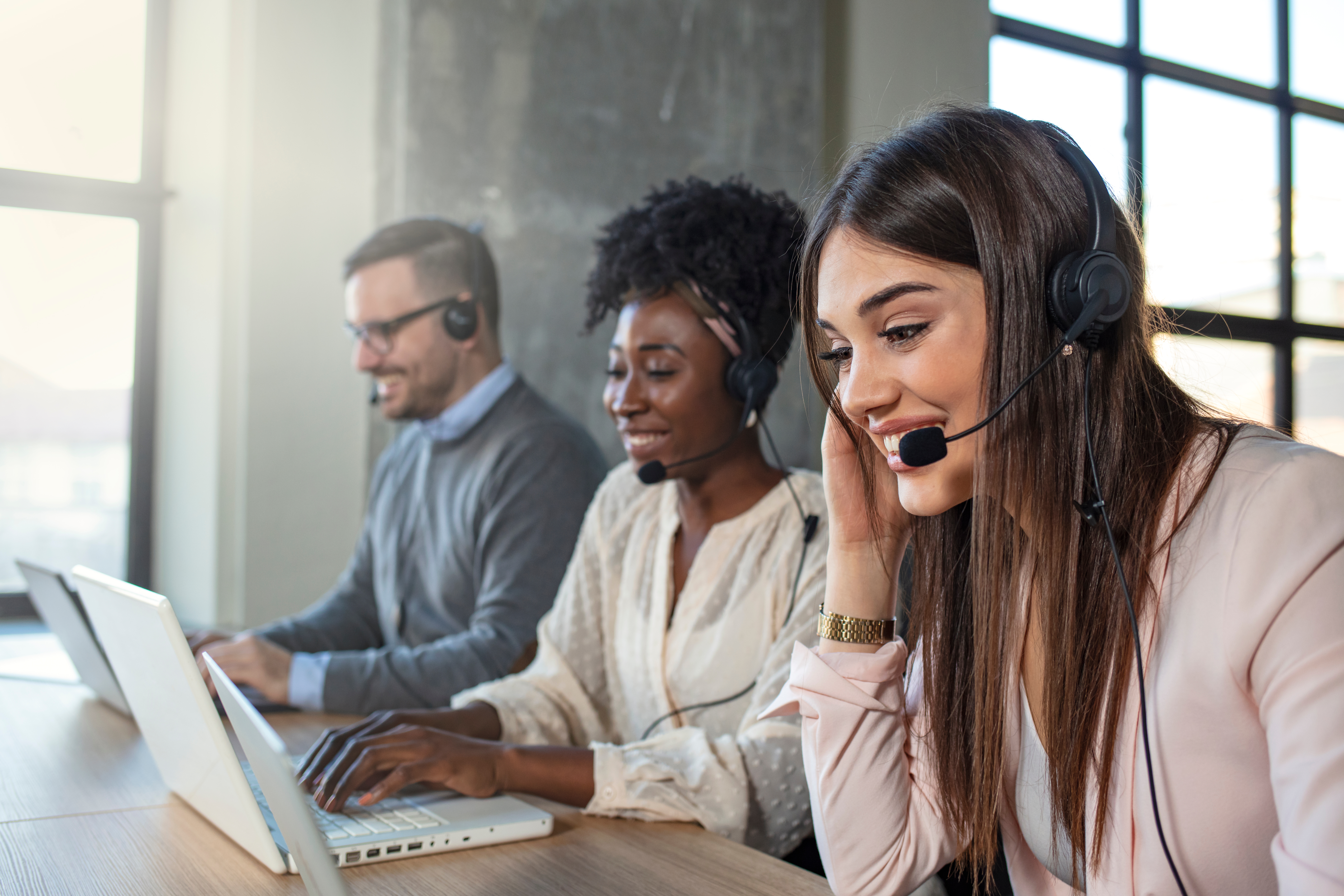 Customer service reps with headsets and computers, smiling