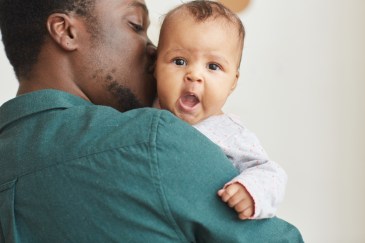 Man holding baby, kissing cheek