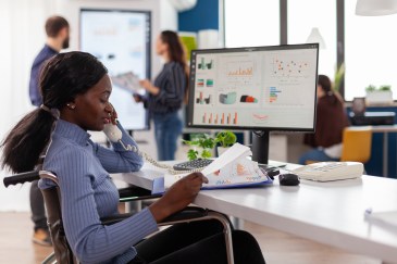 Black woman at her desk in front of financial charts