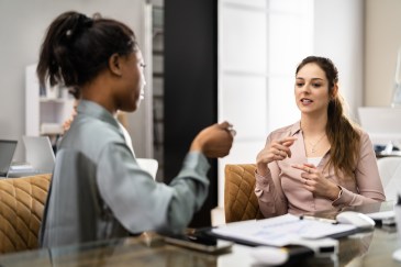 Two female employees talking in office