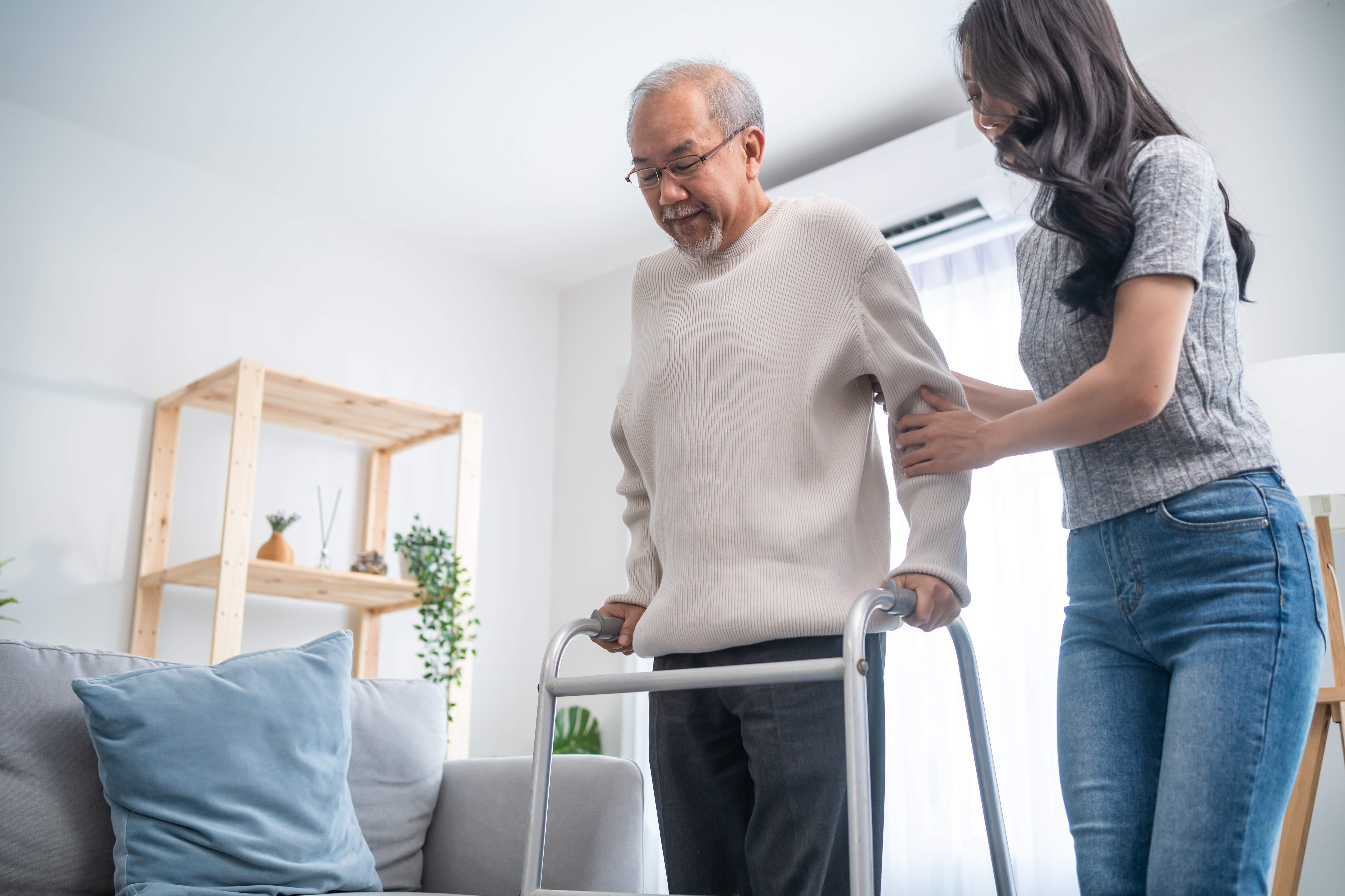 Young woman helping older man using a walker