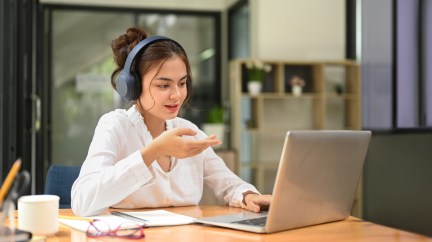 Woman wearing headphones while working on computer