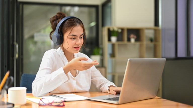 Woman wearing headphones while working on computer