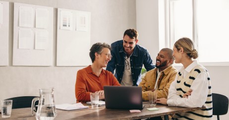 Group of employees sitting at table talking, smiling