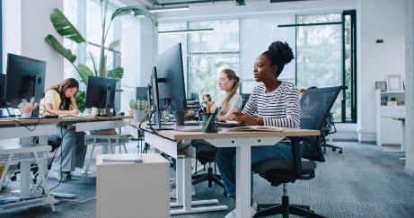 A modern workplace with people at their desks in an open space.