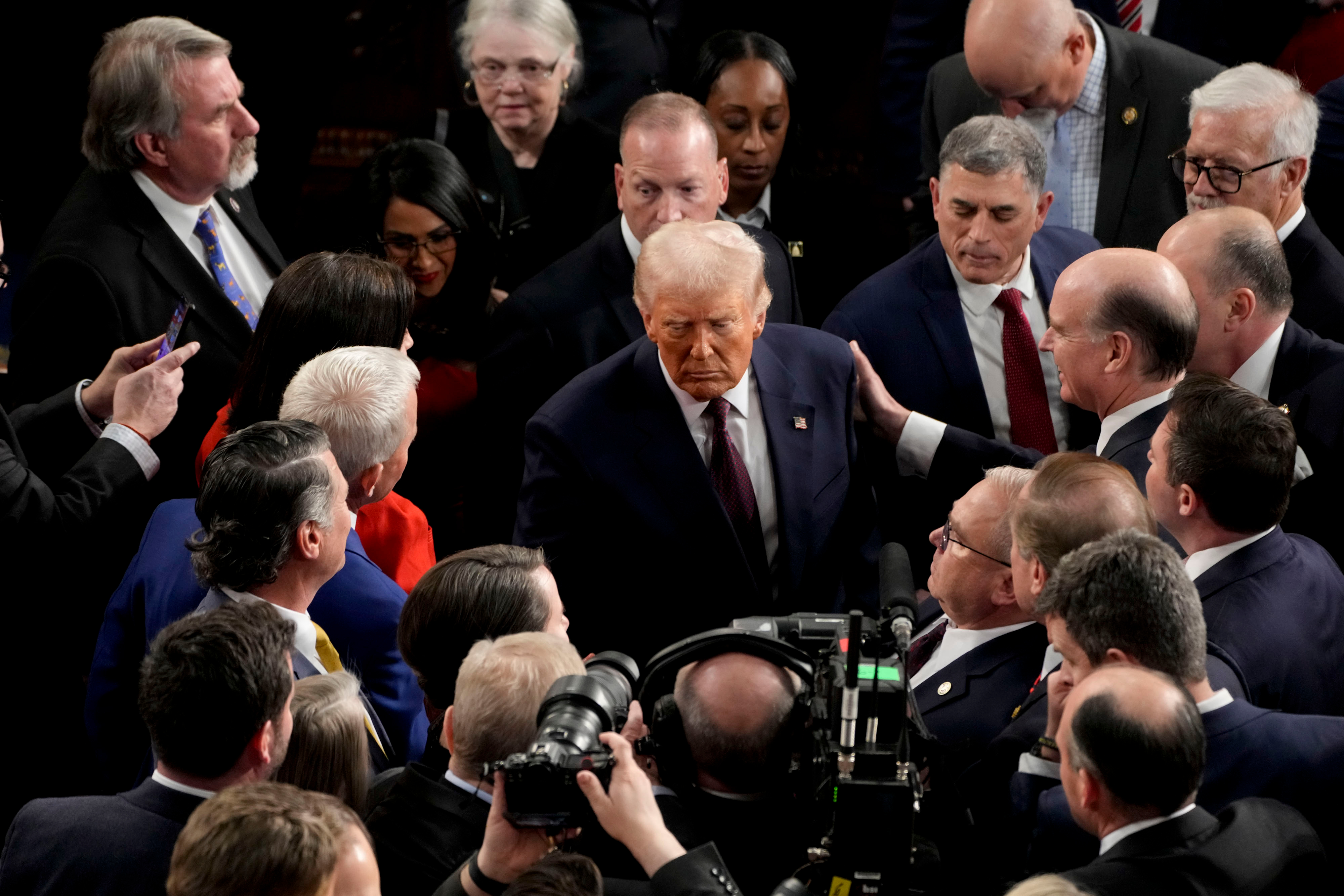 U.S. President Donald Trump departs following a joint session of Congress in the House Chamber while the crowd begins to engulf him.
