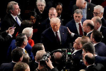 U.S. President Donald Trump departs following a joint session of Congress in the House Chamber while the crowd begins to engulf him.