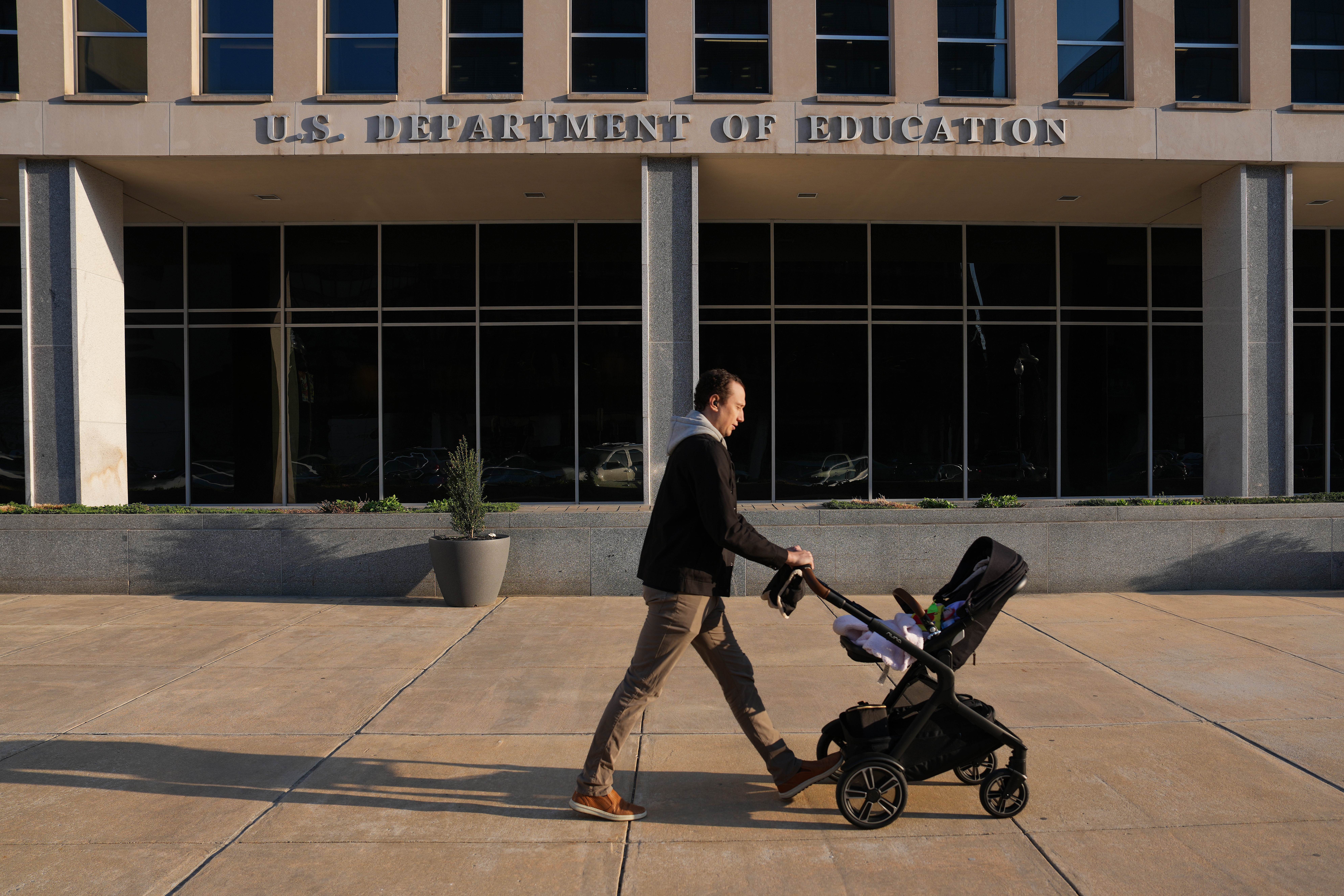 Man pushing a stroller in front of the Department of Education