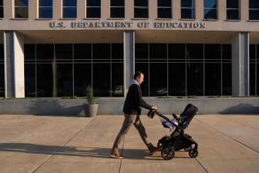 Man pushing a stroller in front of the Department of Education