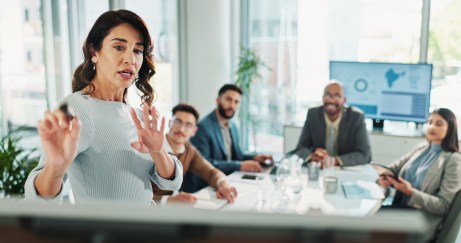 Leader, standing, speaking to employees sitting at table