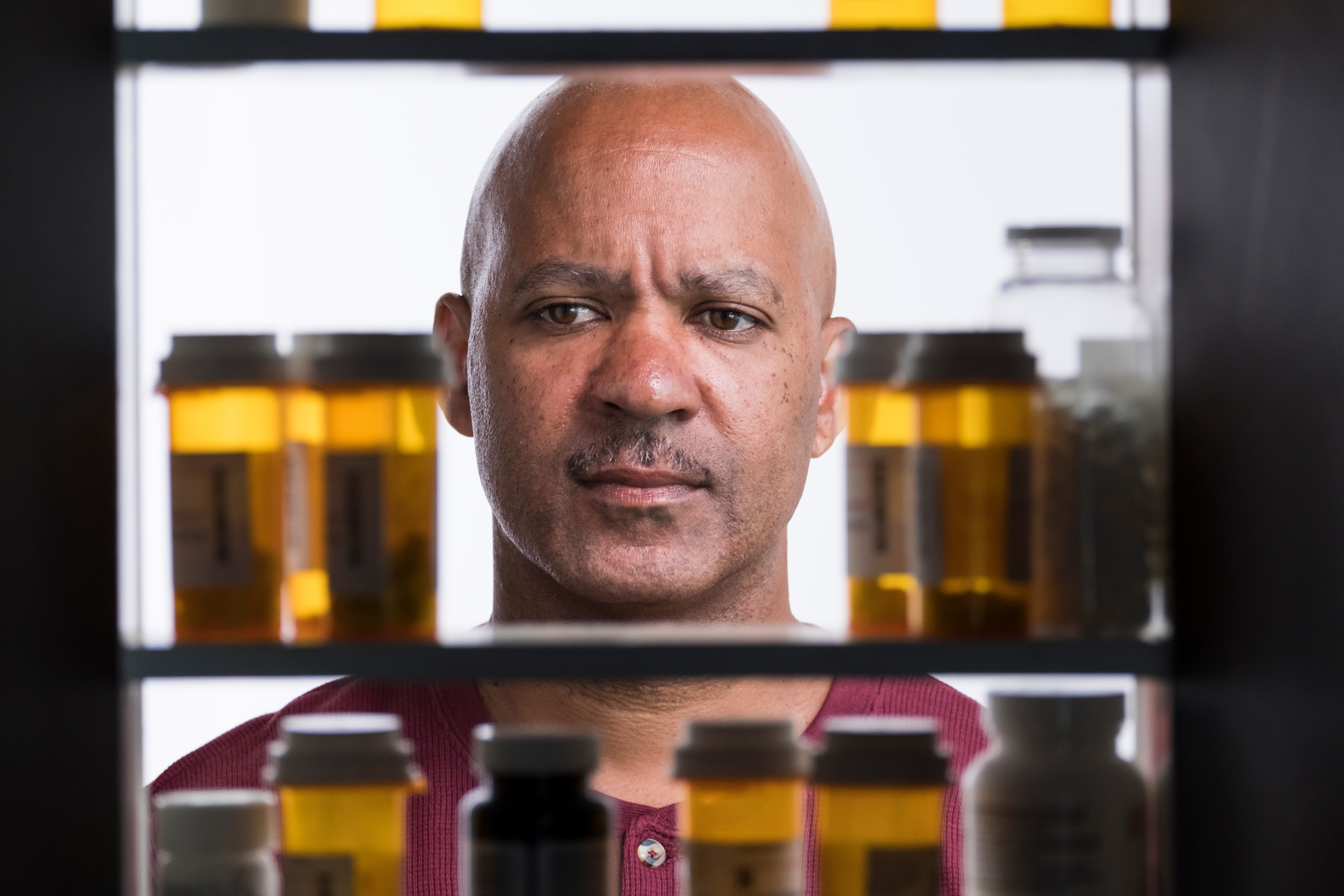 Man looking into medicine cabinet with numerous prescription bottles