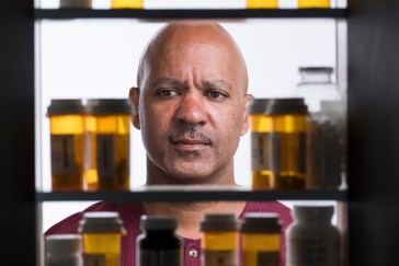 Man looking into medicine cabinet with numerous prescription bottles