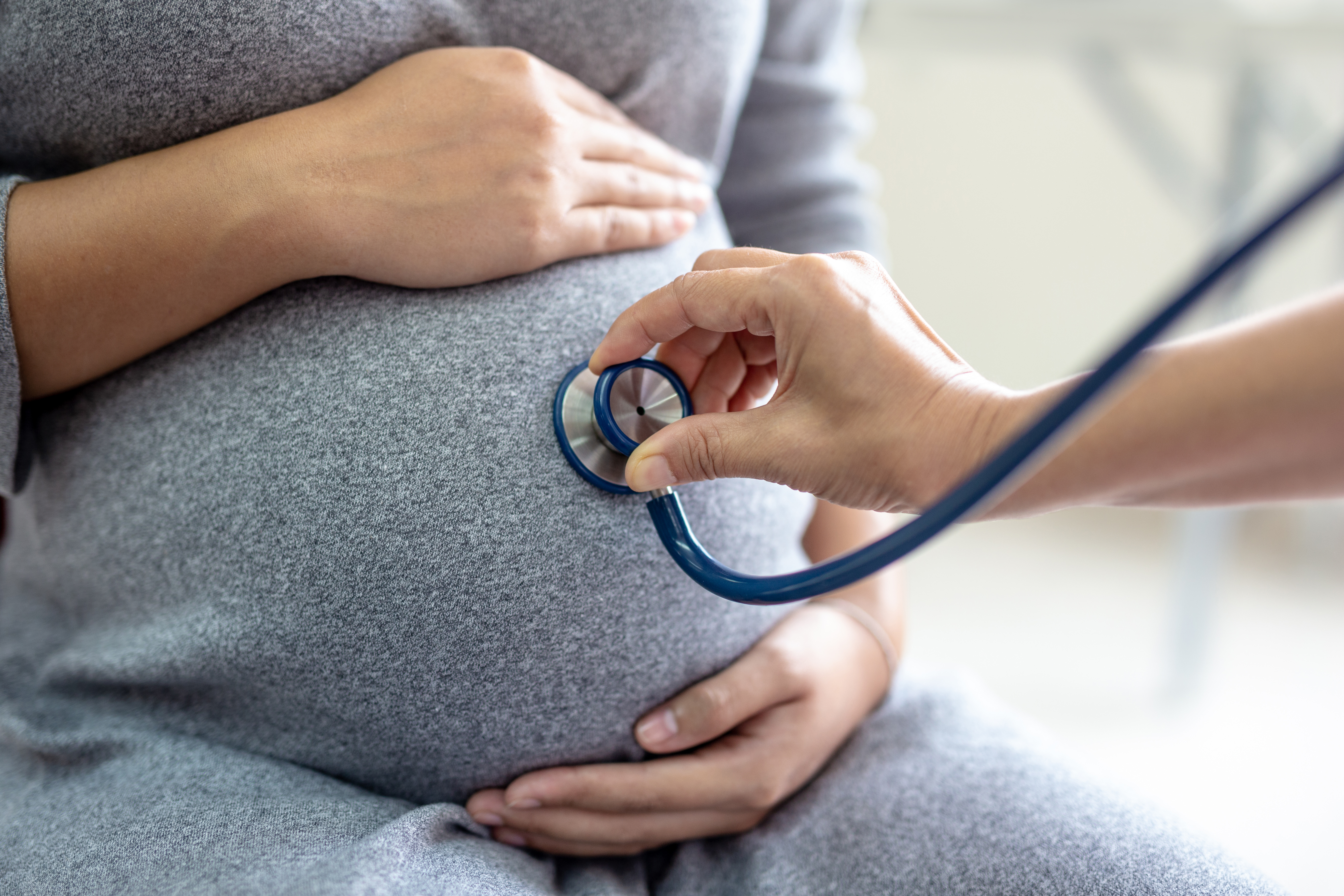 A doctor is using a stethoscope on a pregnant woman's stomach.