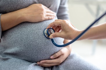 A doctor is using a stethoscope on a pregnant woman's stomach.
