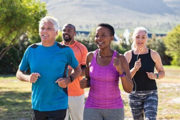 A group of four people jogging together in a park during the day.