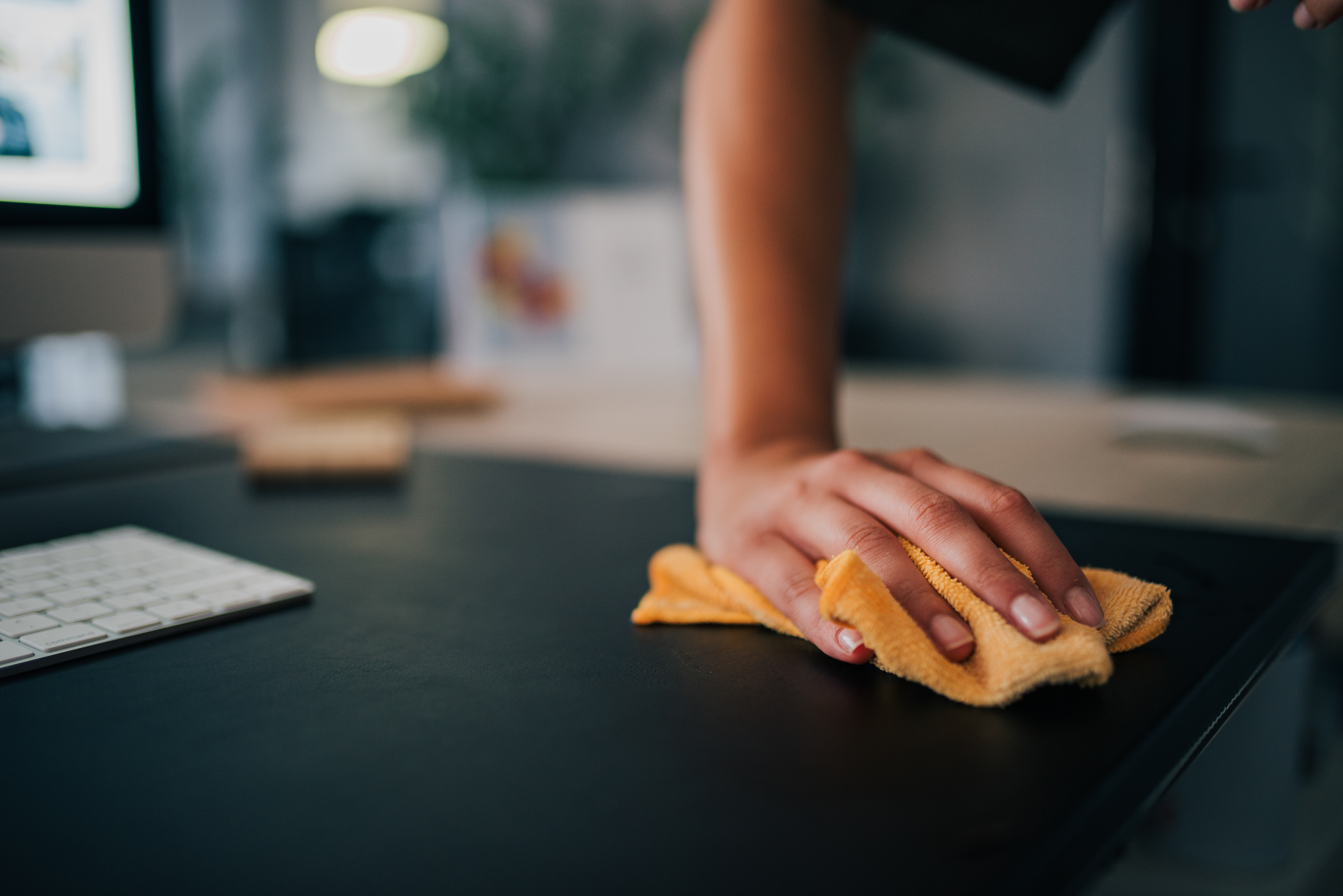 Woman wiping down a desk with a cleaning rag