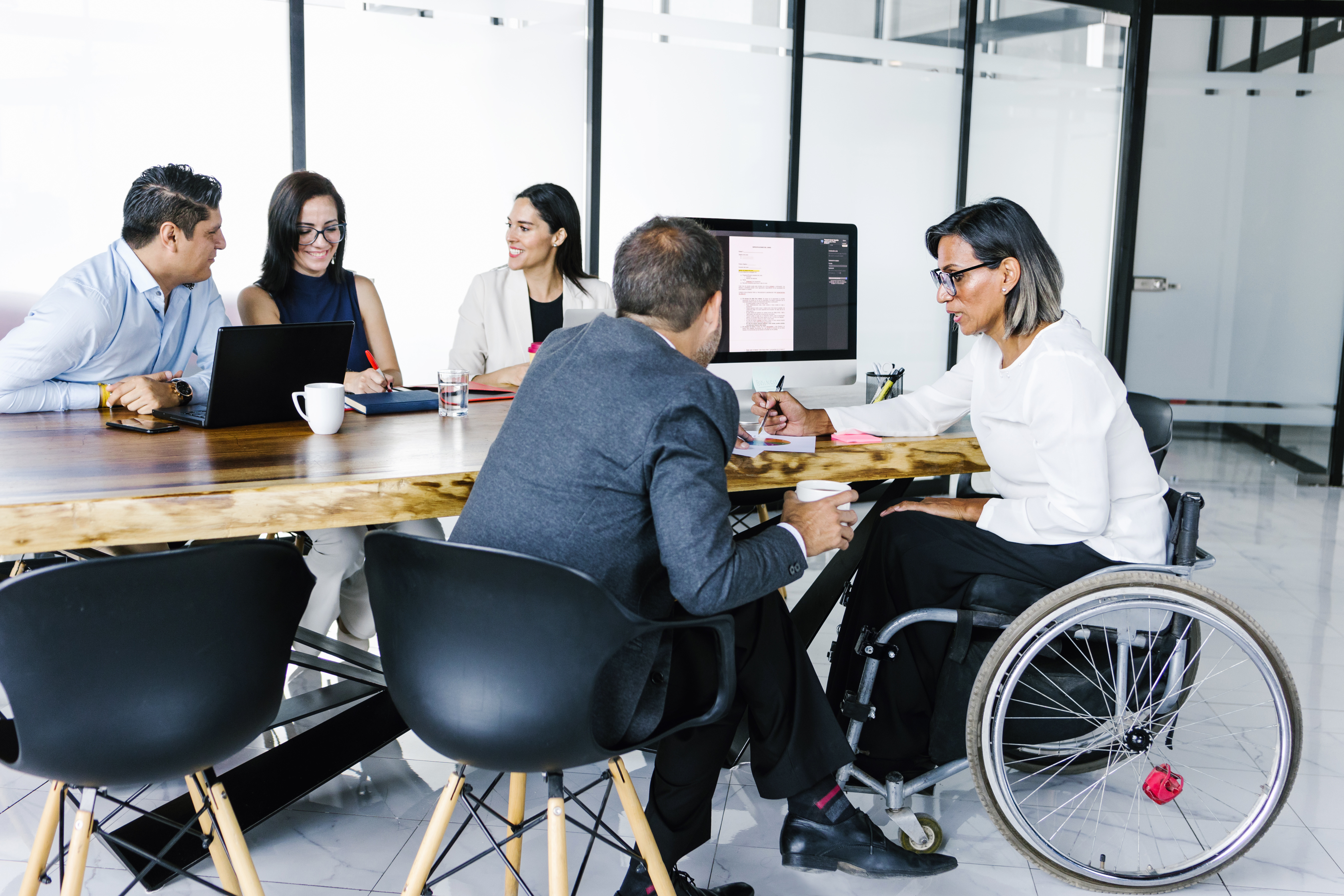 Group of employees sitting at table, working, woman in wheelchair